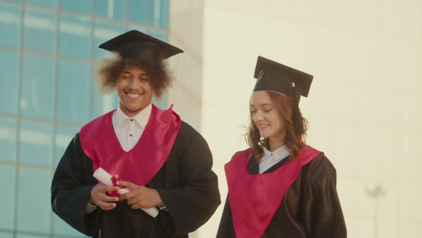 Positive Successful Graduates Happy Throw Up the Graduation Caps while Walking on Background of College. They are Feeling Great All Together. Concept of Moment of Graduation Celebration