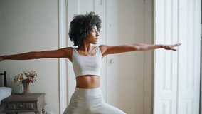 Calm model practicing yoga at home. African american relaxed girl making asana pose looking distance at white place. Slim sportswoman stretching body having morning workout at bedroom. Sport concept - Powered by Shutterstock - Get 15% off with code: PIKWIZARD15