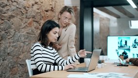 Video of wo beautiful designer women working with laptop while choosing materials in digital tablet in the modern office.