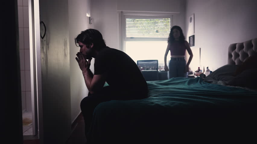 Couple Arguing and Fighting. Man feeling pressure by Female Partner. girlfriend in background discussing relationship while depressed man sits by the bedside feeling frustration