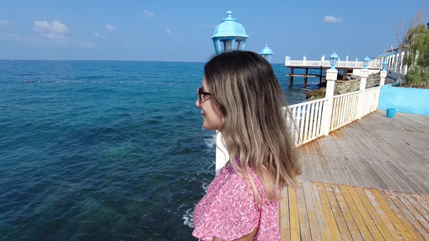 The woman wearing a polka dot dress watches the place where she goes for vacation. Woman wearing sunglasses and mini skirt is on summer vacation.