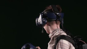A close-up of a boy in a VR headset immersed in virtual reality in a game studio, he circles around himself and watches a video with glasses. A new generation headset for entertainment.