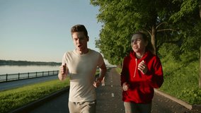 Sport couple run together in park. Young people jogging together at fitness training outdoor. Man and woman at sport training together. Brunette and blonde run. New life after quarantine. Girls keep a