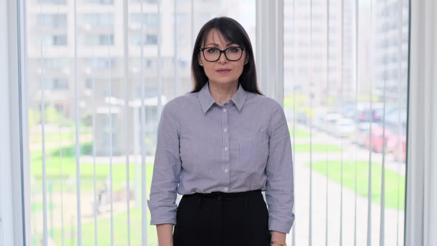 Middle age business woman with crossed arms, in office near window