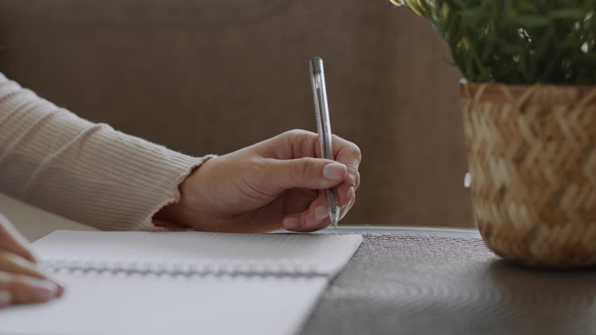 Close up shot of unrecognizable left-handed woman writing in copy book, studying at desk at home, free space Royalty-Free Stock Footage #1103258809