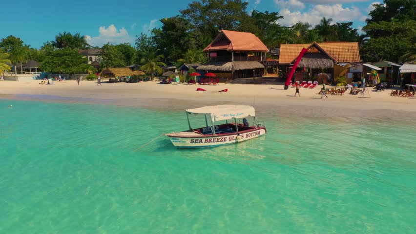 Aerial view of motor boat is moored on the Seven Mile Beach in Negril, Jamaica. Shooting from the air.  Royalty-Free Stock Footage #1103259755