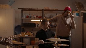 WIDE HANDHELD Friends playing music during their rock band rehearsal repetition inside a garage. Vocals, guitars and drums. Shot with 2x anamorphic lens - Powered by Shutterstock - Get 15% off with code: PIKWIZARD15
