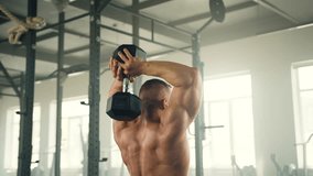 Back view of athletic man with muscular bare torso doing overhead tricep extension. Man exercises in light spacious fully-equipped. Slow motion. High quality 4k footage - Powered by Shutterstock - Get 15% off with code: PIKWIZARD15