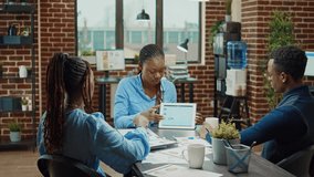 Business analyst explaining statistics, giving presentation in boardroom meeting space with digital tablet. African american team of employees examining online company analytics for development. - Powered by Shutterstock - Get 15% off with code: PIKWIZARD15