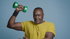 Sports mature african american man athlete with dumbbell in blue background studio athletic trainer sportive coach sportsman blogger talking to camera explain showing exercise for biceps sport blog