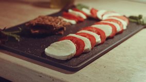 Steam transformation effect of Caprese - italian national dish. Sliced tomatoes and mozarella arranged in shape of Christmas candy cane. Served with basil and olive oil. Slowmotion