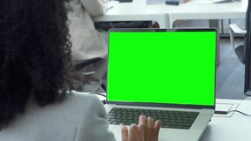 Young business woman working on laptop with blank copy space screen for ad app in modern busy office. Over shoulder view on businesswoman using touchscreen of computer with green chromakey mockup. - Powered by Shutterstock - Get 15% off with code: PIKWIZARD15