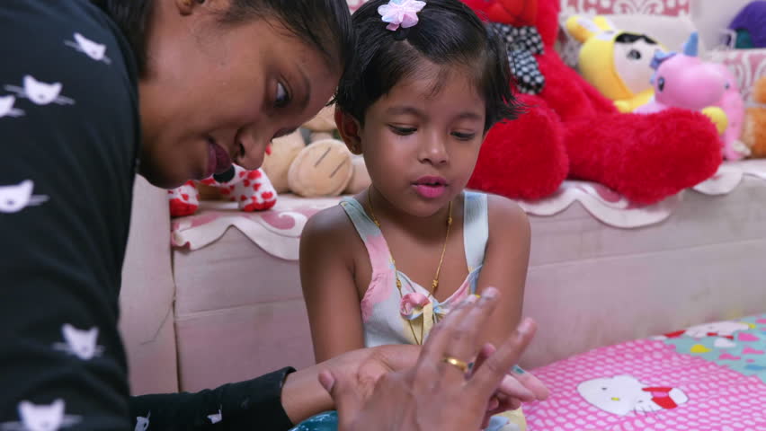 This video is about mother and daughter looking each other while mom coloring her hand background filled with soft toys