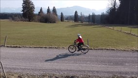 Video with a drone of a cyclist on a dirt road in springtime