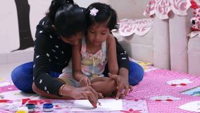 This video is about Mom and kid drawing with sponge and daughter sitting on her Lap and painting