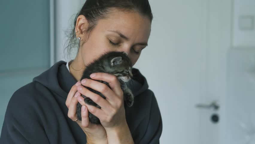 portrait of a woman kissing a kitten
