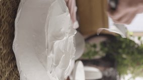 close up of female hand finishing the meringue coverage of a cake, rotating base