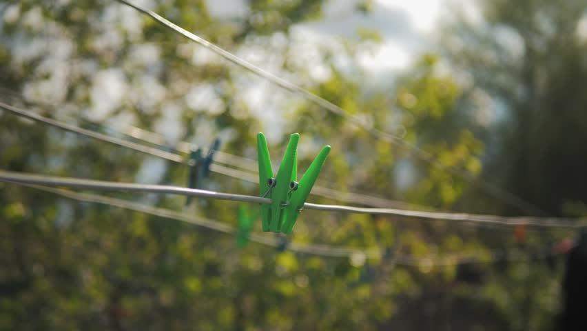 woman hanging clothes on clothesline. A person hangs clothes after washing on a clothesline, a clothesline with clothespins on which clothes hang. Domesticity. Clothes after washing.