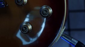 Adjusting tone knobs and volume of electric guitar, close up. Vertical video. Musician guitarist adjusting knobs on guitar, preparing to play songs. Volume and tone controls of wooden electric guitar - Powered by Shutterstock - Get 15% off with code: PIKWIZARD15