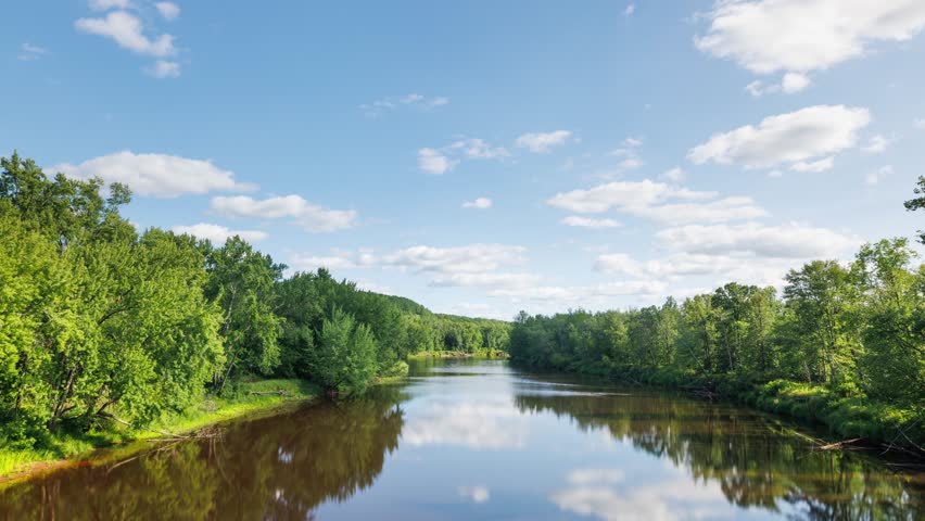 Time lapse of the clouds moving above Kettle River surrounded by forest in Minnesota.