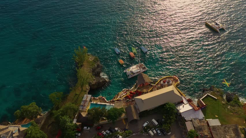 Aerial view of Ricks Cafe in Negril, Jamaica and Rocky west coast. Many people and nearby cafes have several boats and catamaran.