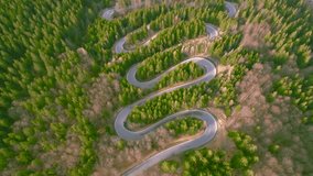 Aerial view of a winding road in the mountains shoot from a drone while picking up altitude. The video was shoot with the camera tilted downwards for a top view of the serpentines and the traffic.