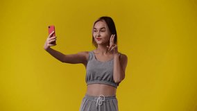 4k video of beautiful girl making selfie on yellow background.