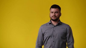4k video of man pointing at left and showing thumb up over yellow background.