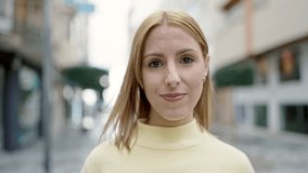 Young blonde woman standing with serious expression at street