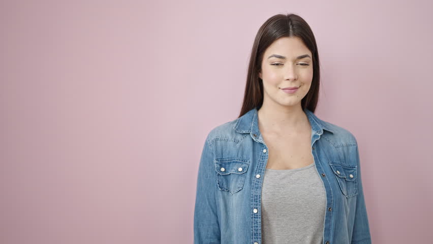Young beautiful hispanic woman smiling confident pointing with finger to the side over isolated pink background