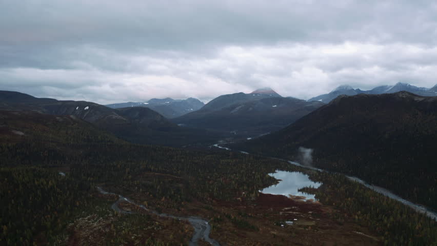 Aerial view of the natural reserve on an autumn day. Clip. Mountain range and heavy cloudy sky above forested valley.
