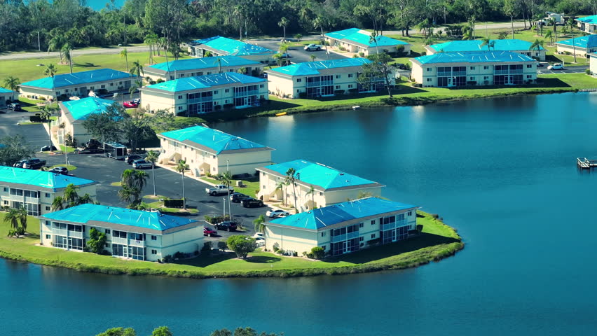 Aerial view of damaged in hurricane Ian apartment building roofs covered with blue protective tarp against rain water leaking until replacement of asphalt shingles Royalty-Free Stock Footage #1103310383