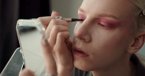 Transgender guy doing eye make up using a brush and mirror Video stock