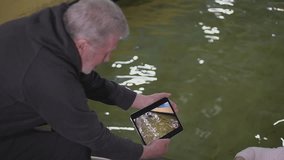 an elderly coach sitting on a chair shows the athlete a video on the tablet. error parsing. close-up. slow motion video. canoe slalom. High-quality FullHD video recording
