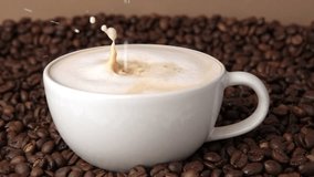 Drop of milk falling in a white cup with black coffee. Side View. Slow Motion. Coffee droplet. Roasted coffee beans background. Freshly brewed latte cappuccino. Close up. Coffee product advertising. - Powered by Shutterstock - Get 15% off with code: PIKWIZARD15
