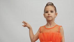 Cute little girl in orange dress posing over white background. Little princess girl portrait, 4k slow motion
