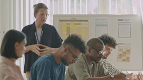 Female teacher walking around diverse migrant students and talking to them during exam in language school - Powered by Shutterstock - Get 15% off with code: PIKWIZARD15