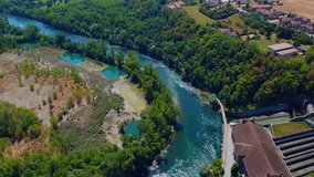 Aerial view of a mountain freshwater river surrounded by green trees at a hydroelectric power station. Green energy on the planet. Ecology. The rocky bottom of the river. drone video. Trezzo sull'Adda