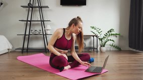 Workout at home. Young woman girl with sporty figure, uses laptop, watches video lesson of fitness.