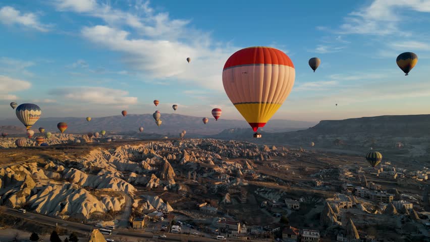 Drone - Hot Air Balloons, Cappadocia, Turkey 2023 - Flying towards red and white air balloon high with others over the city Royalty-Free Stock Footage #1103338495