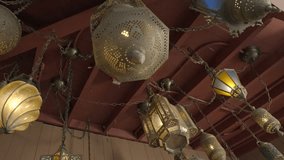 This panning video shows a room's ceiling with scattered old exotic moroccan lanterns and pendant lights. 