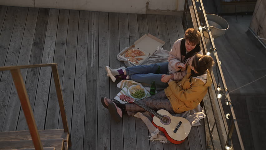 4k Lesbian couple has good time on rooftop in city spbd. Top view of beautiful lgbt woman holding hands and talking, looking with smiles and sitting on roof with food and drinks. Young homosexual | Shutterstock HD Video #1103341211