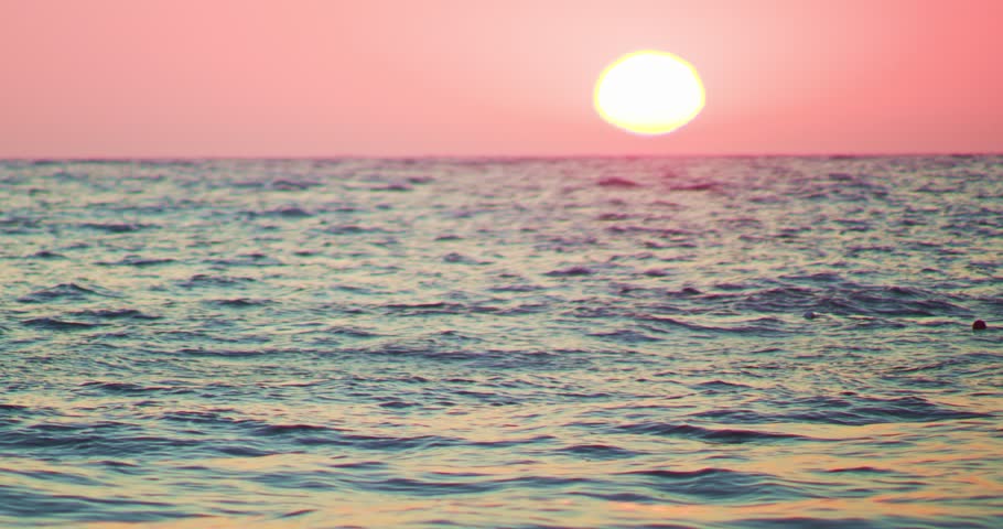 The sun setting over the horizon on the background of the sea, the reddish hue of sunset