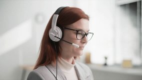 technical support, young woman call center operator is talking with client on a microphone on headphones while sitting in coffee shop