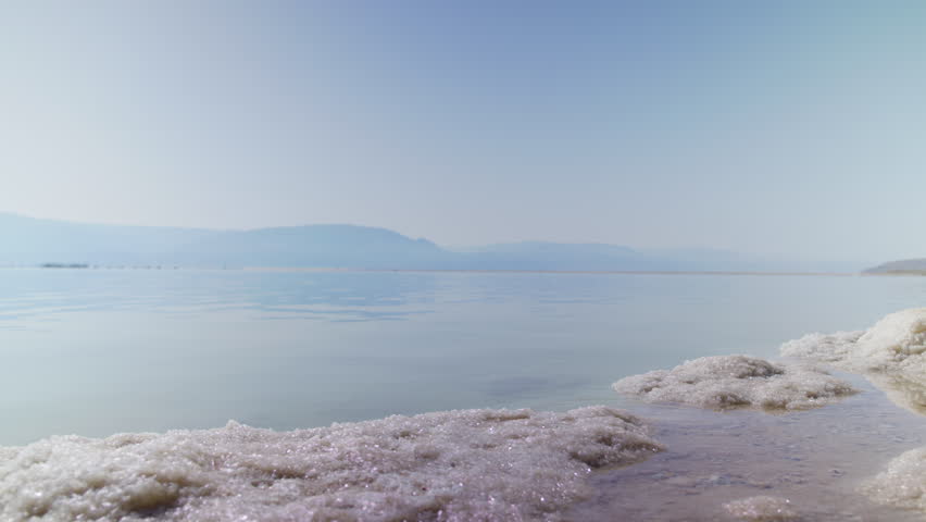 timelapse of slat water movement of the Dead Sea in the early morning - low angle with salt blocks in the foreground