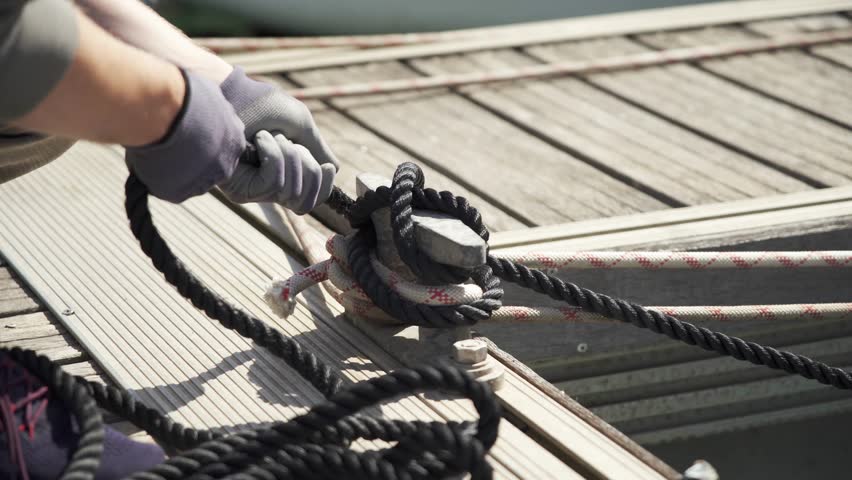 A man wearing gloves ties a strong cleat hitch. Knot for cleat dock. Close-up. Mooring knot. Sailor. Sailing boat.Sailboat mooring. 4K Royalty-Free Stock Footage #1103346507