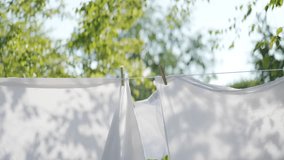 White sheets held up with clothes pegs on a washing line outside