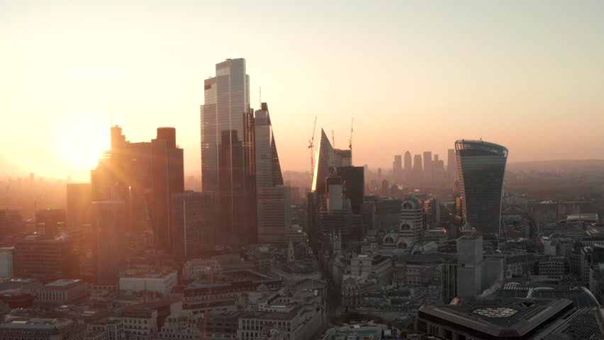 Aerial slider shot City of London skyscrapers at dawn to the Thames revealing Canary Wharf. Royalty-Free Stock Footage #1103351341