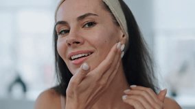 Smiling woman enjoying skin condition at bath portrait. Beauty girl touching perfect face after applying cream pov video view. Young lady looking camera closeup. High self esteem and wellness concept