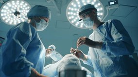 Male plastic surgeon and nurse discussing course of plastic surgery procedure in operating room. Patient is on table. Led theatre operation lights. High quality 4k footage if - Powered by Shutterstock - Get 15% off with code: PIKWIZARD15